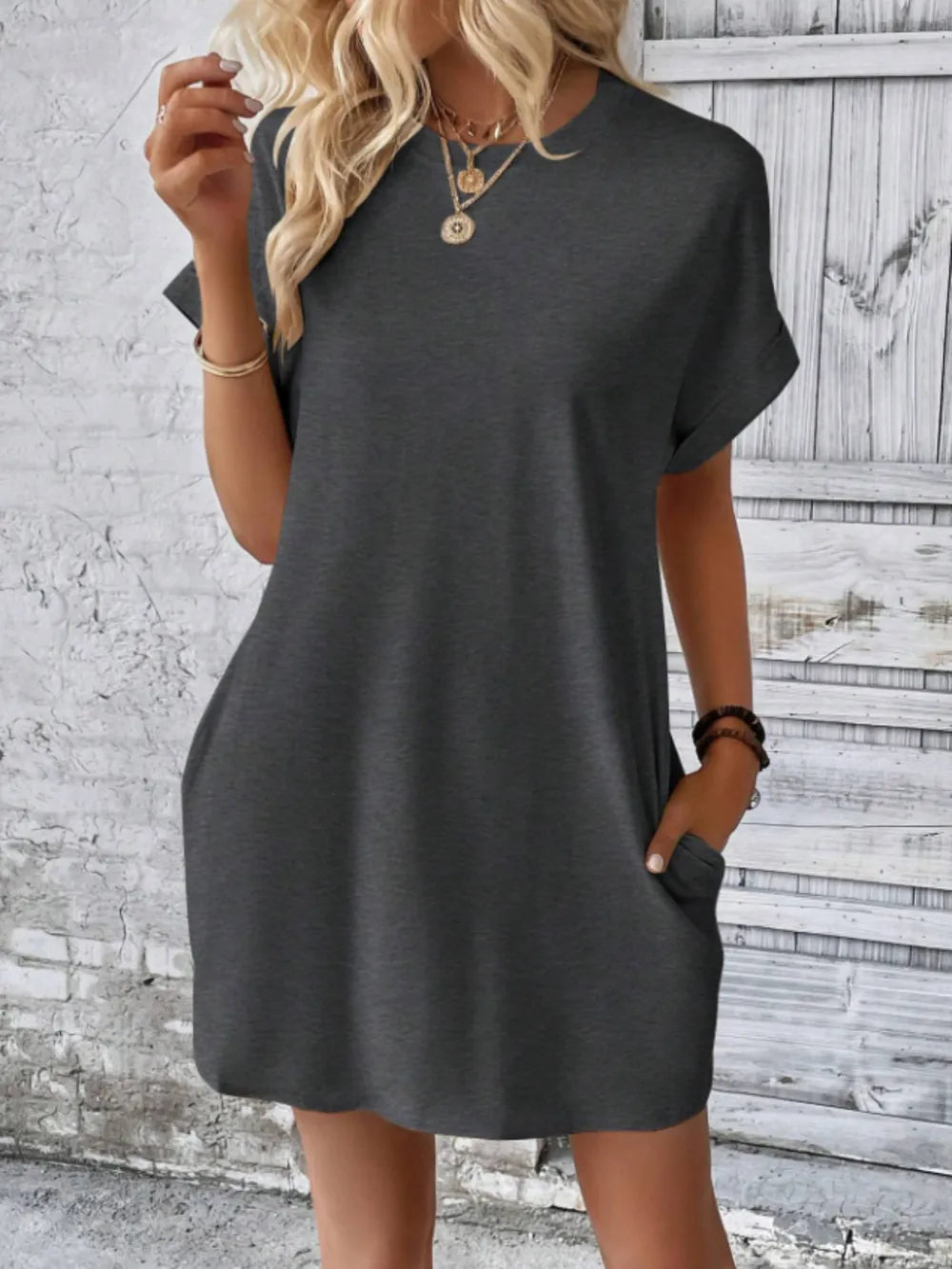 Woman wearing a gray dress against a textured wall.