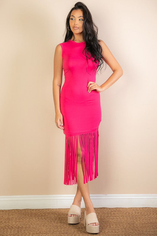 Woman wearing a bright pink dress with fringe details against a beige wall.