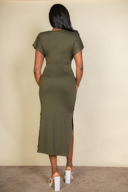 Woman wearing a green dress with a backless design against a beige wall.