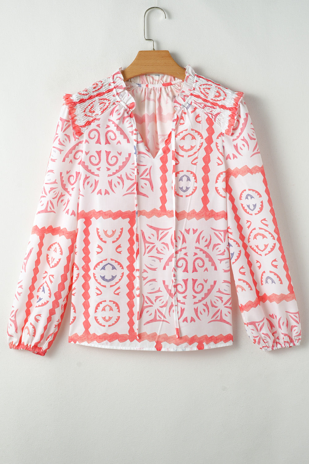 White blouse with red patterns on a hanger against a white background