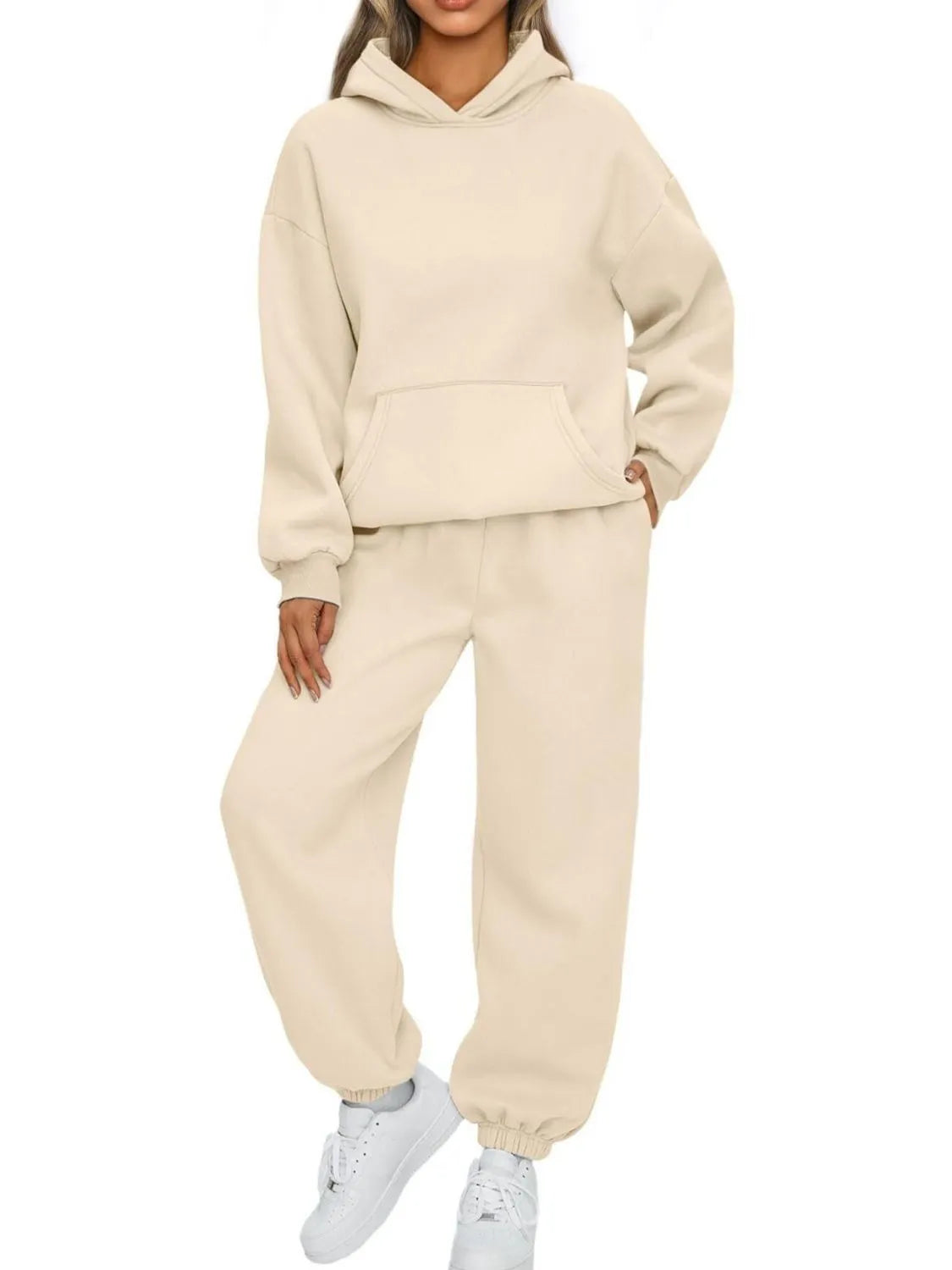 Person wearing a beige hoodie and jogger set on a white background