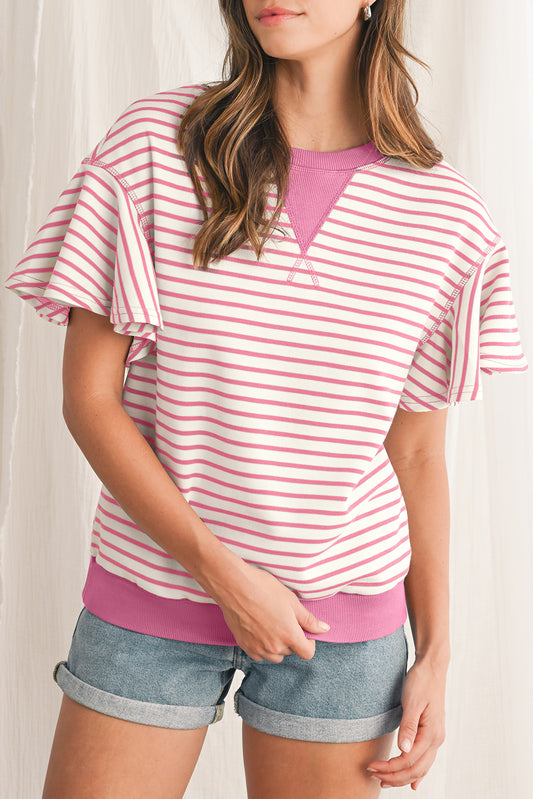Woman wearing a pink and white striped shirt with denim shorts on a plain background