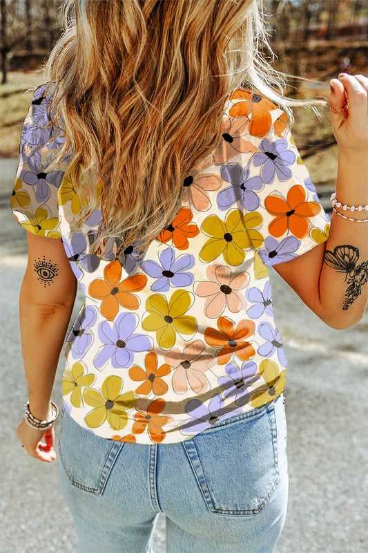 Person wearing a colorful floral shirt with tattoos on arms outdoors.