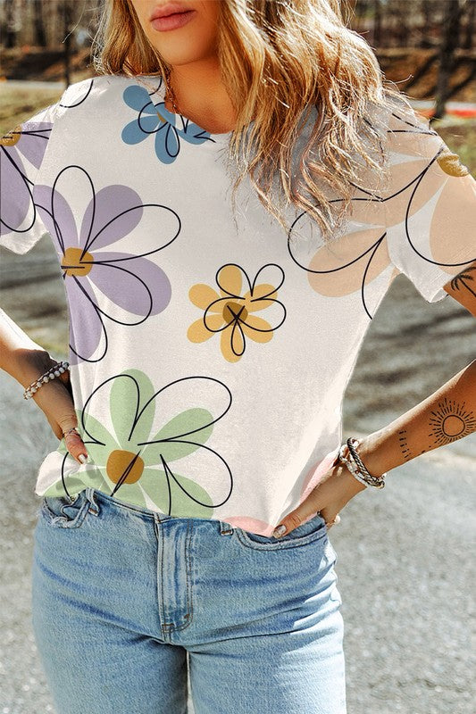 Person wearing a white t-shirt with colorful floral patterns and blue jeans outdoors.