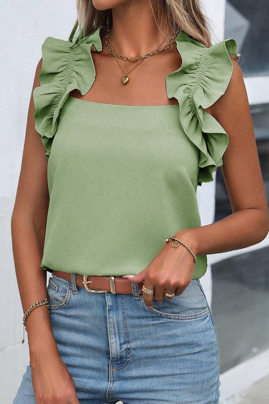 Person wearing a green top with ruffled shoulders and blue jeans.