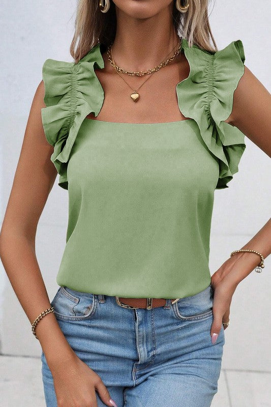 Woman wearing a green top with ruffled sleeves and blue jeans against a white background
