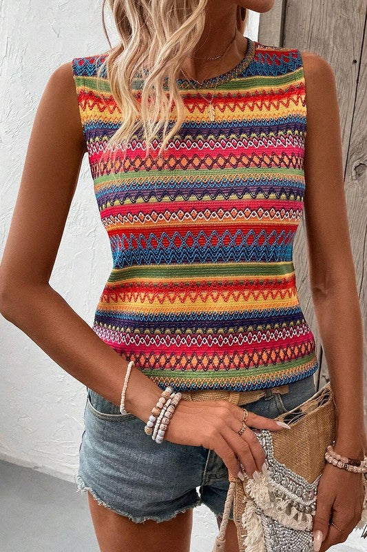 Person wearing a colorful striped sleeveless top with denim shorts against a wooden background
