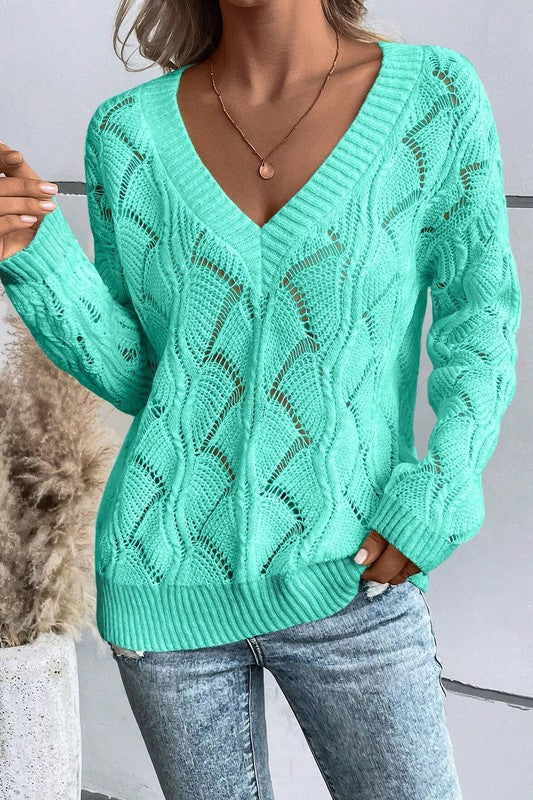 Person wearing a green off-shoulder sweater and blue jeans, holding a coffee cup.reen