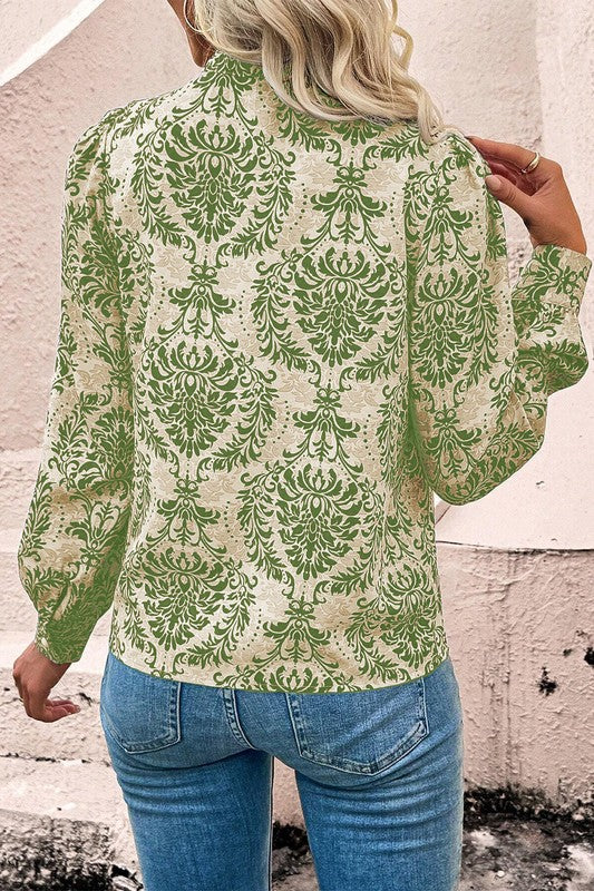 Person wearing a green and beige patterned blouse with blue jeans against a textured wall.