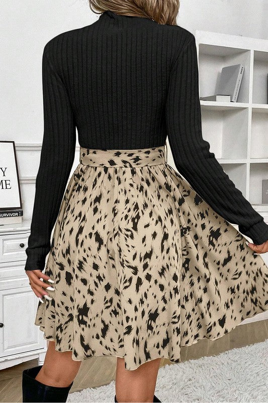 Person wearing a black ribbed sweater and a beige skirt with black animal print in a room.