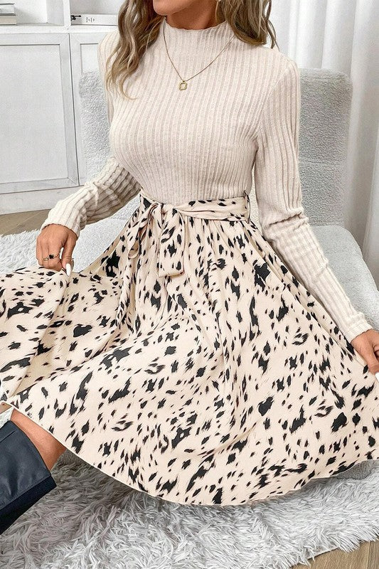 Woman wearing a beige ribbed sweater and leopard print skirt in a home setting.