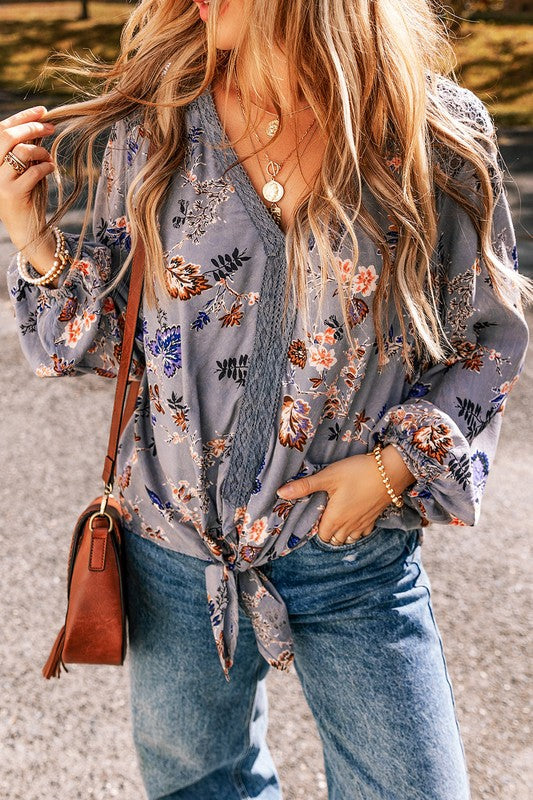 Woman wearing a floral blouse and jeans with a brown leather bag.