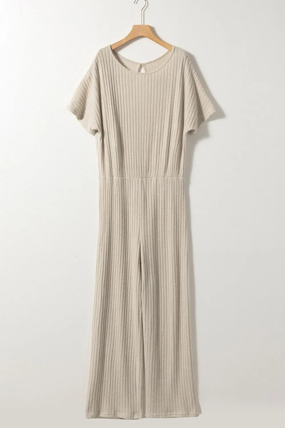 Beige dress on a wooden hanger against a white background