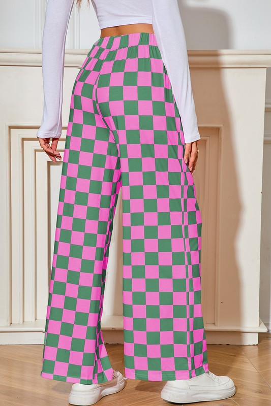 Person wearing pink and green checkered pants with a white top and white shoes.