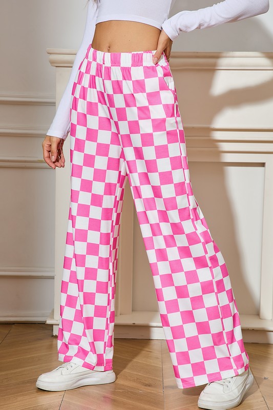 Person wearing pink and white checkered pants with a white top and sneakers indoors.