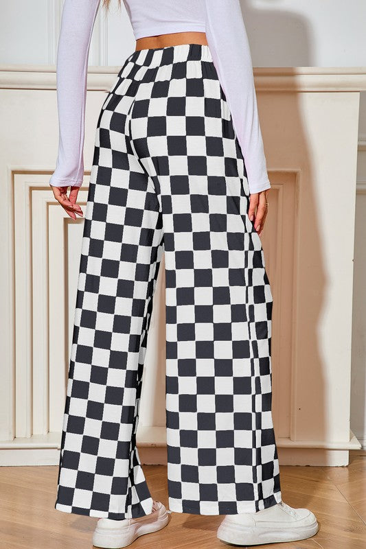 Person wearing black and white checkered pants with a plain background