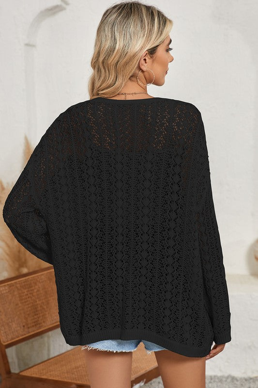 Person wearing a black lace cardigan in an indoor setting