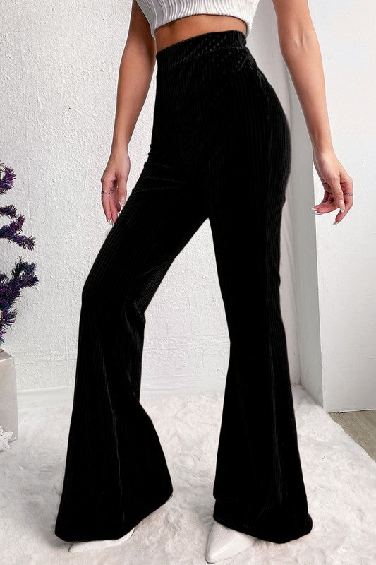 Person wearing black flared pants against a white background