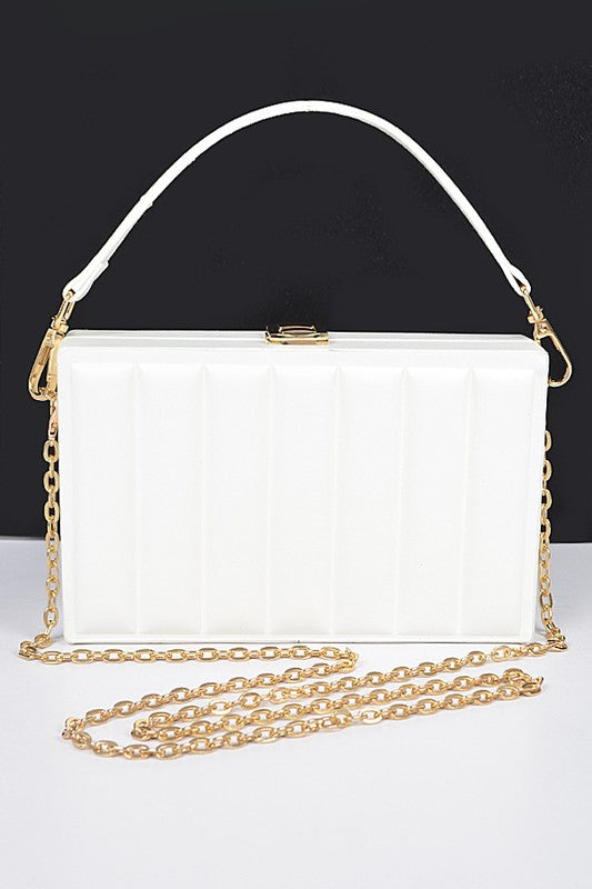 White handbag with gold chain strap on a black background