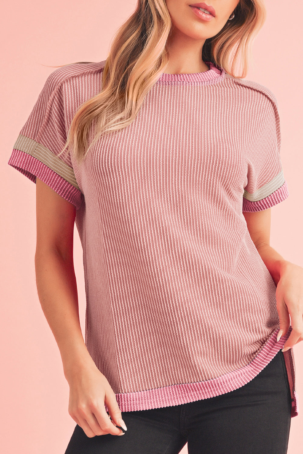 Woman wearing a pink ribbed top with white trim on a pink background