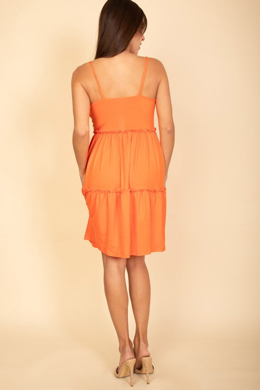 Woman wearing an orange dress against a beige background