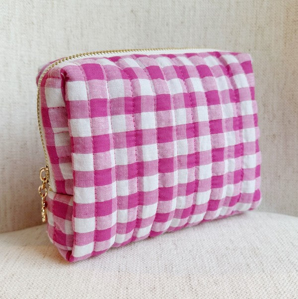 Pink and white checkered pouch with a gold zipper on a beige background