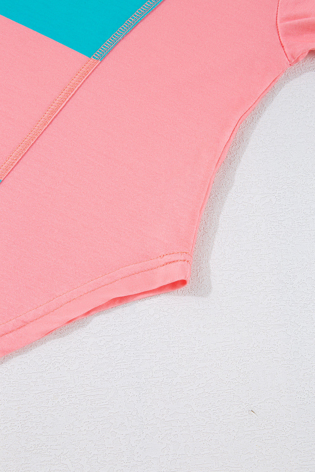 Close-up of a pink garment with a turquoise corner on a light gray background