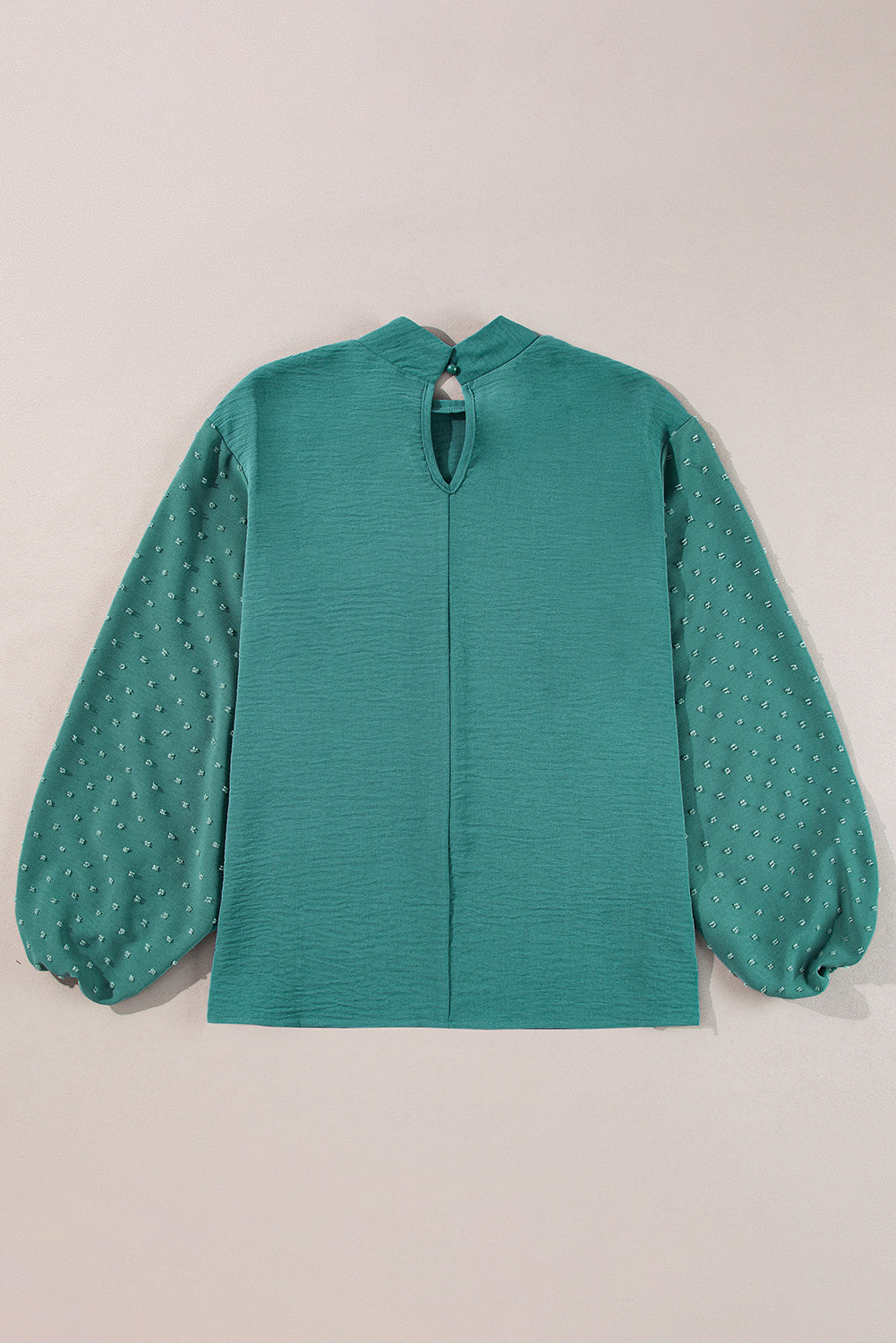 Green blouse with long sleeves on a beige background