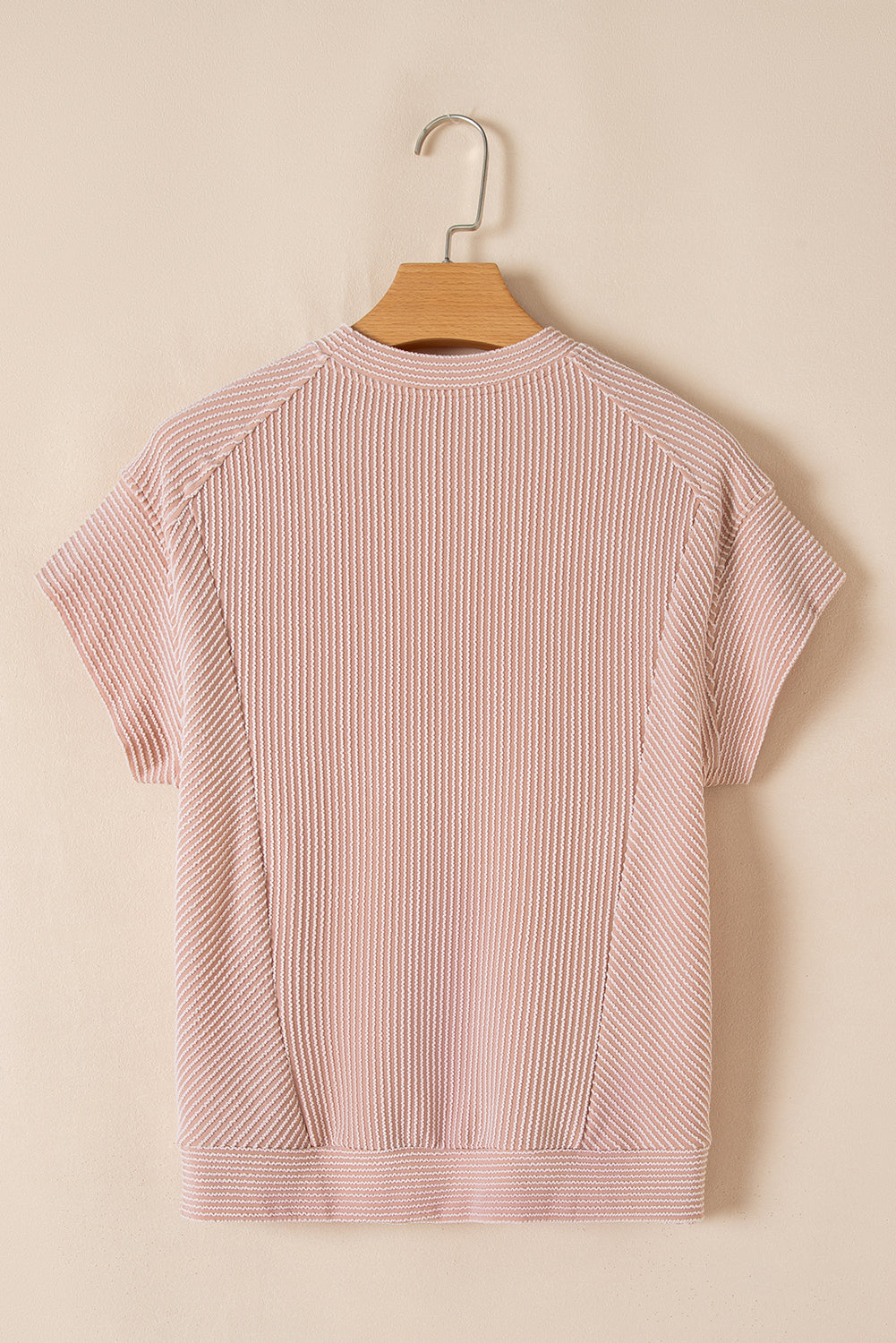 Pink striped shirt on a wooden hanger against a beige background