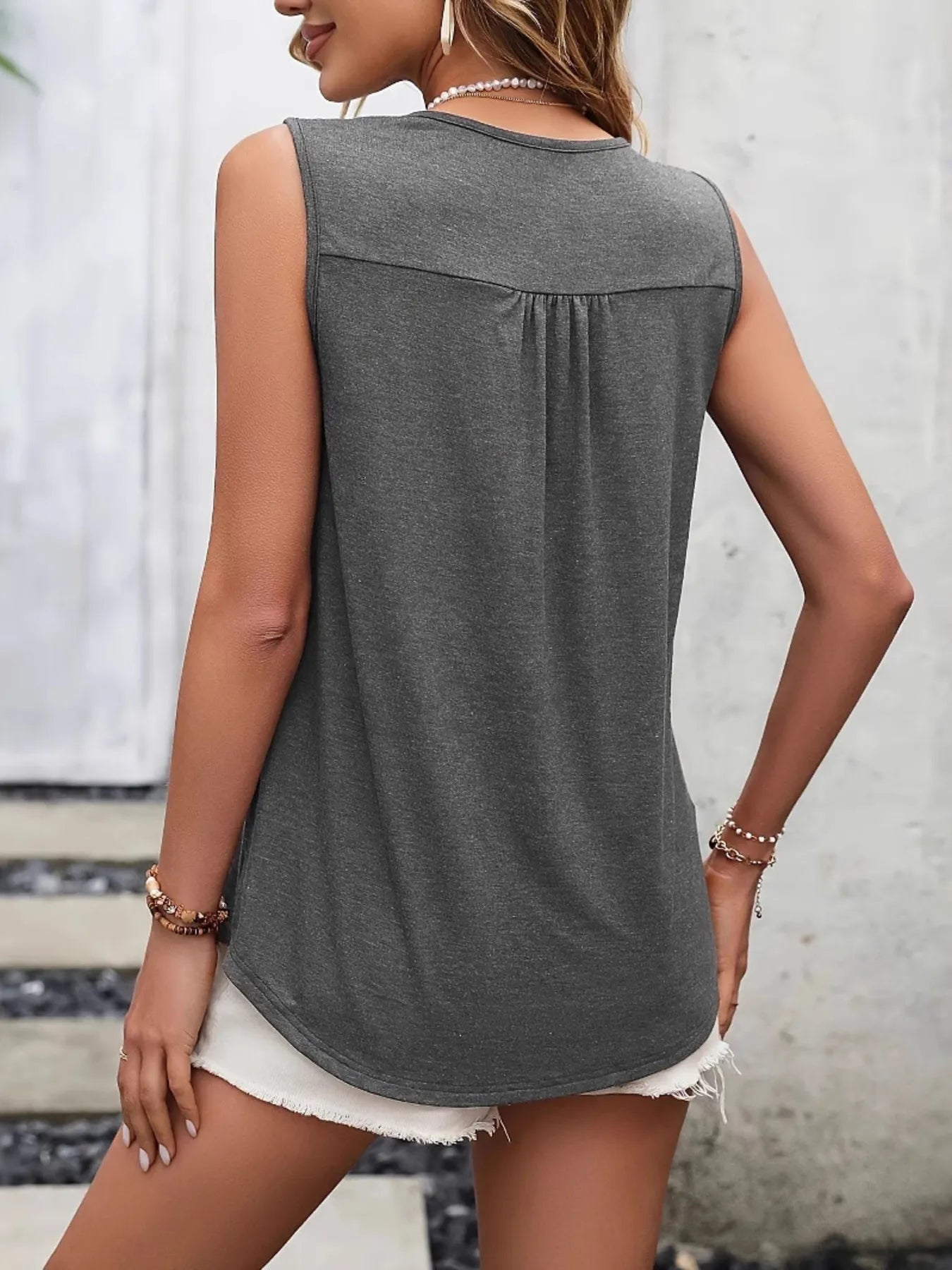 Woman wearing a gray sleeveless top with a blurred background