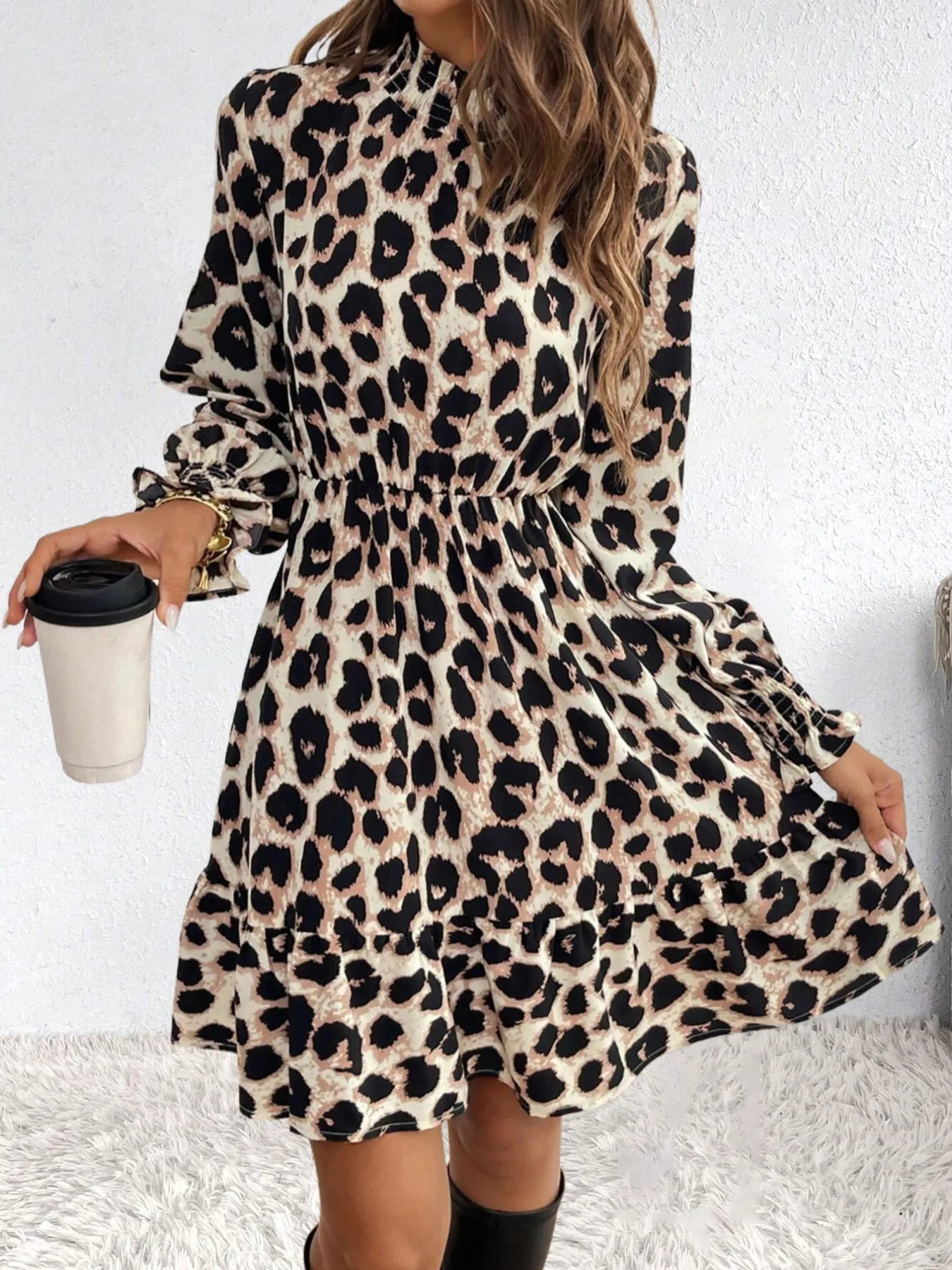 Person wearing a leopard print dress holding a coffee cup against a white background