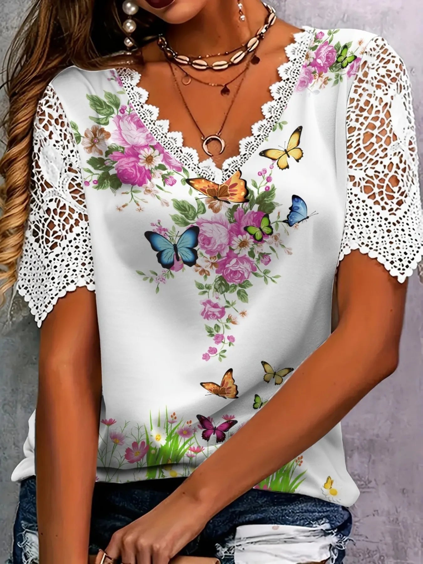 White lace-trimmed top with floral and butterfly designs on a neutral background