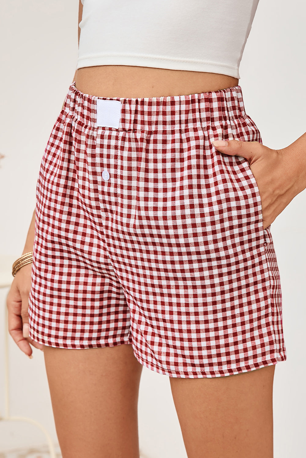 Red and white checkered shorts worn by a person on a light background
