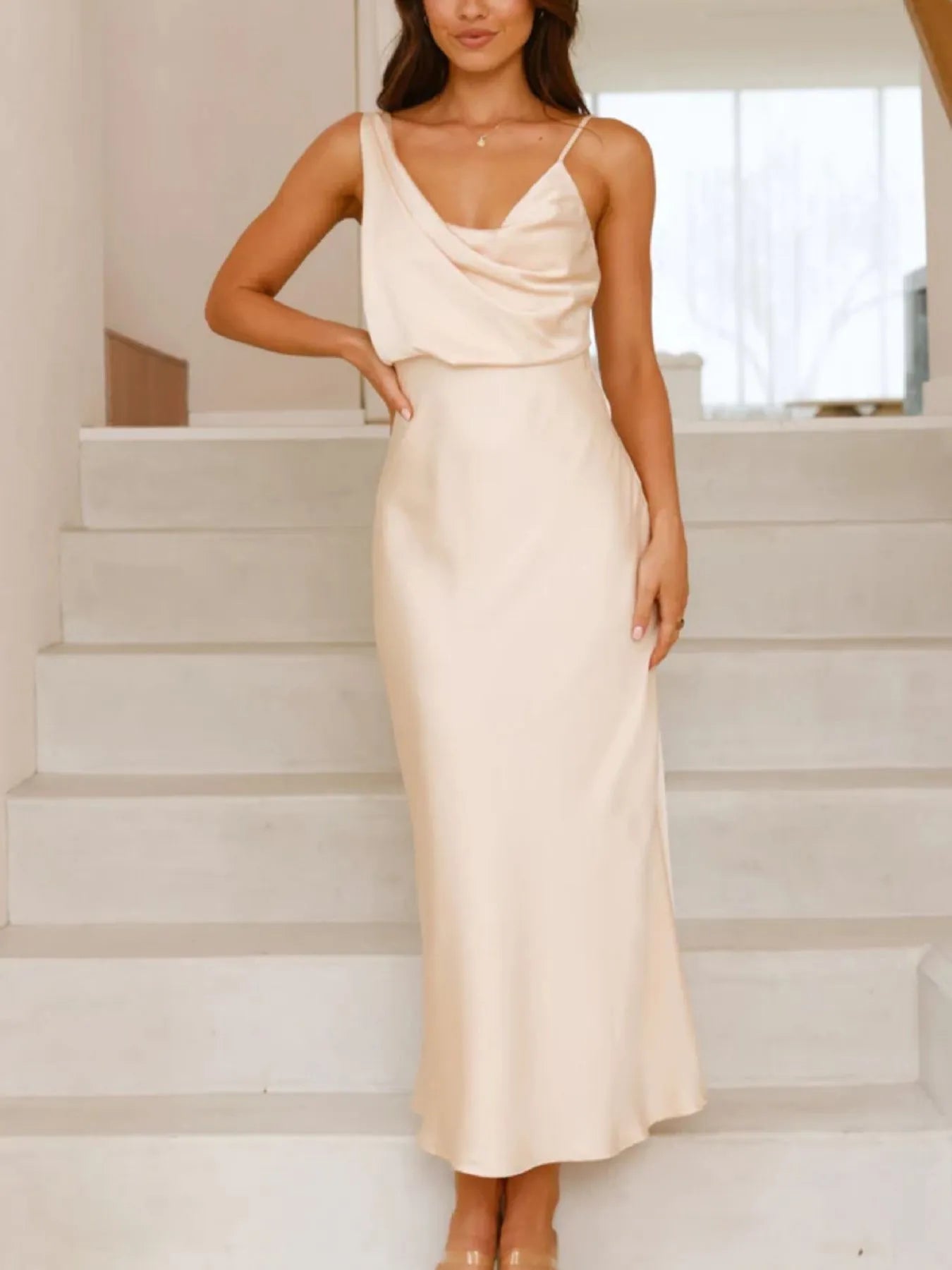 Woman wearing a beige slip dress standing on a staircase.
