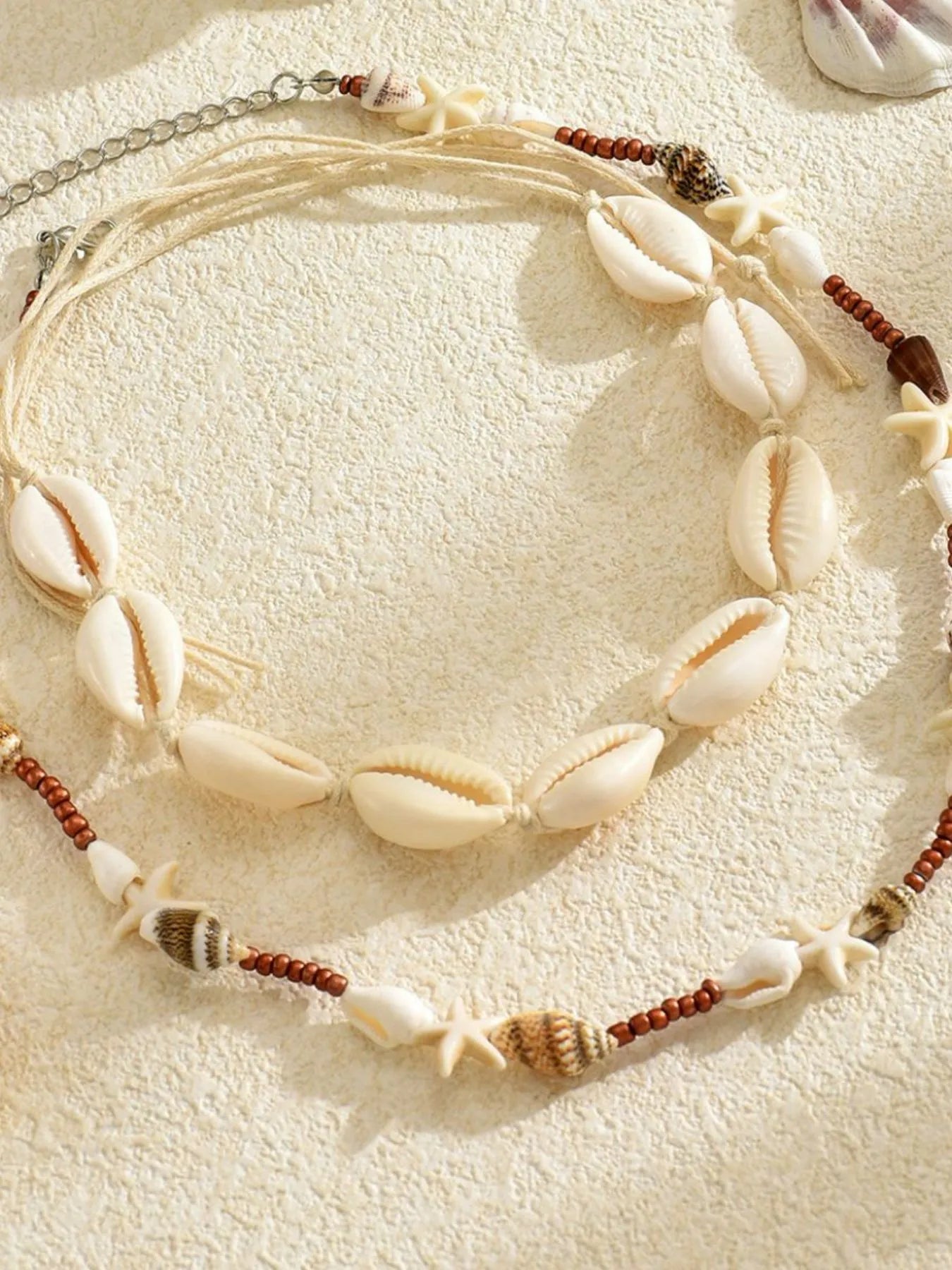 Necklace with shell and bead elements on a textured beige surface