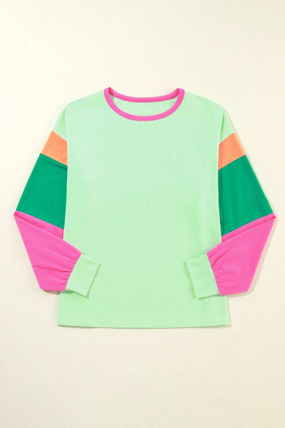 Color-blocked long-sleeve shirt with green, pink, and orange sleeves on a beige background