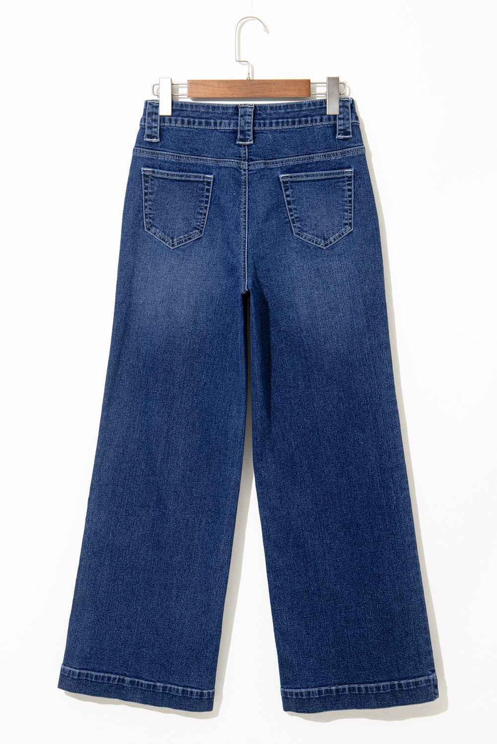 Blue jeans on a hanger against a white background