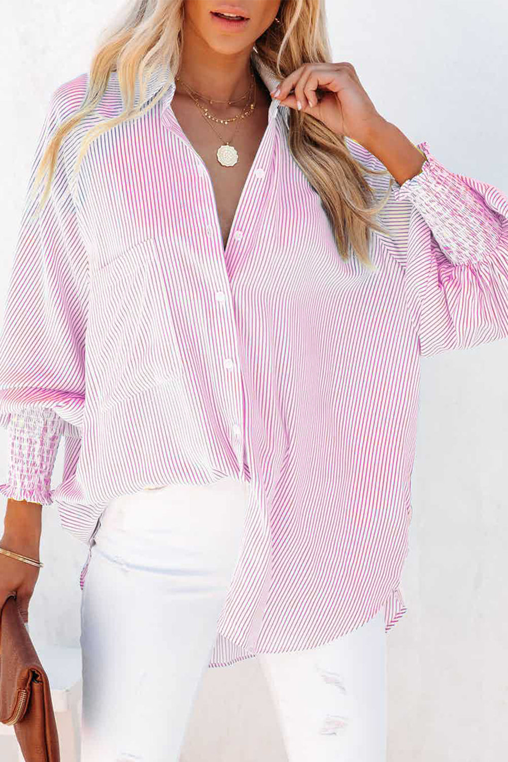 Woman wearing a pink and white striped shirt with white pants on a white background