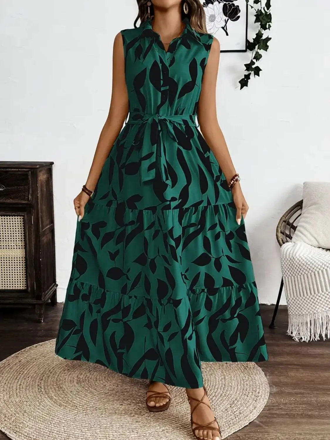 Woman wearing a green dress with black pattern in a room with a fireplace and chair.