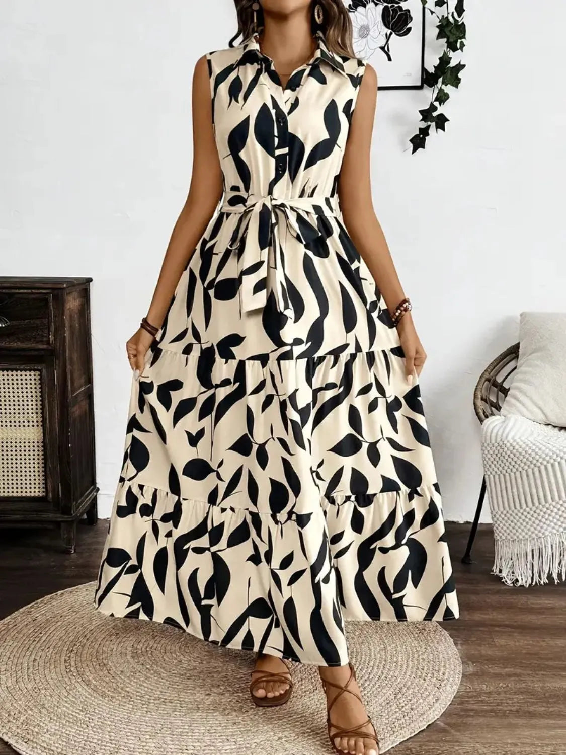 Woman wearing a sleeveless dress with black leaf pattern in a room.