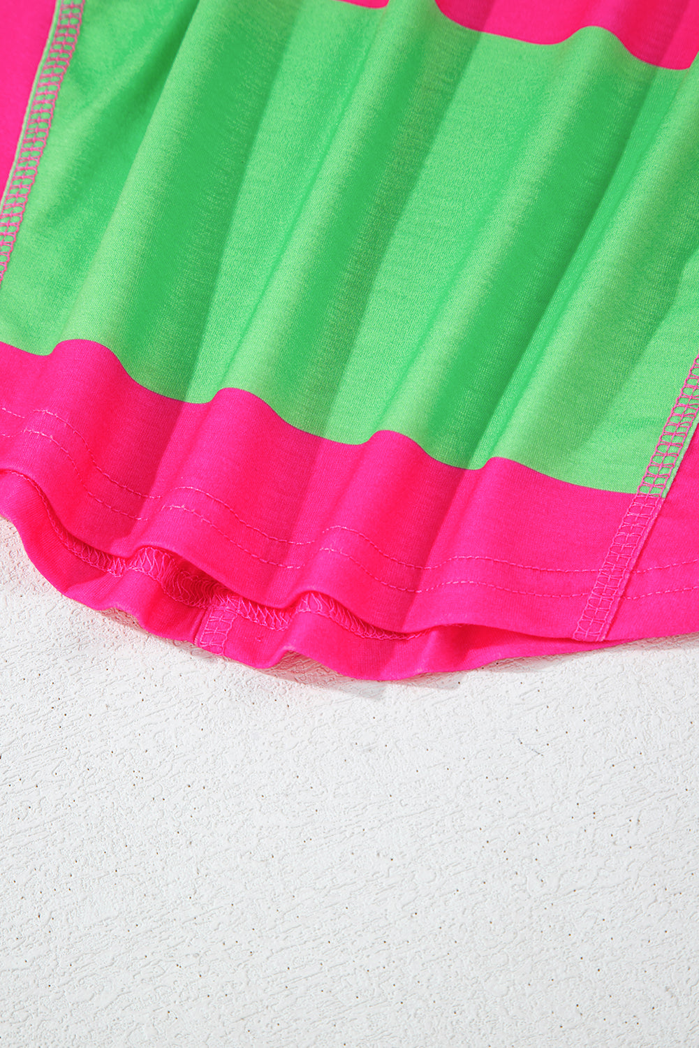 Close-up of a green and pink fabric with ruffled edge on a white background