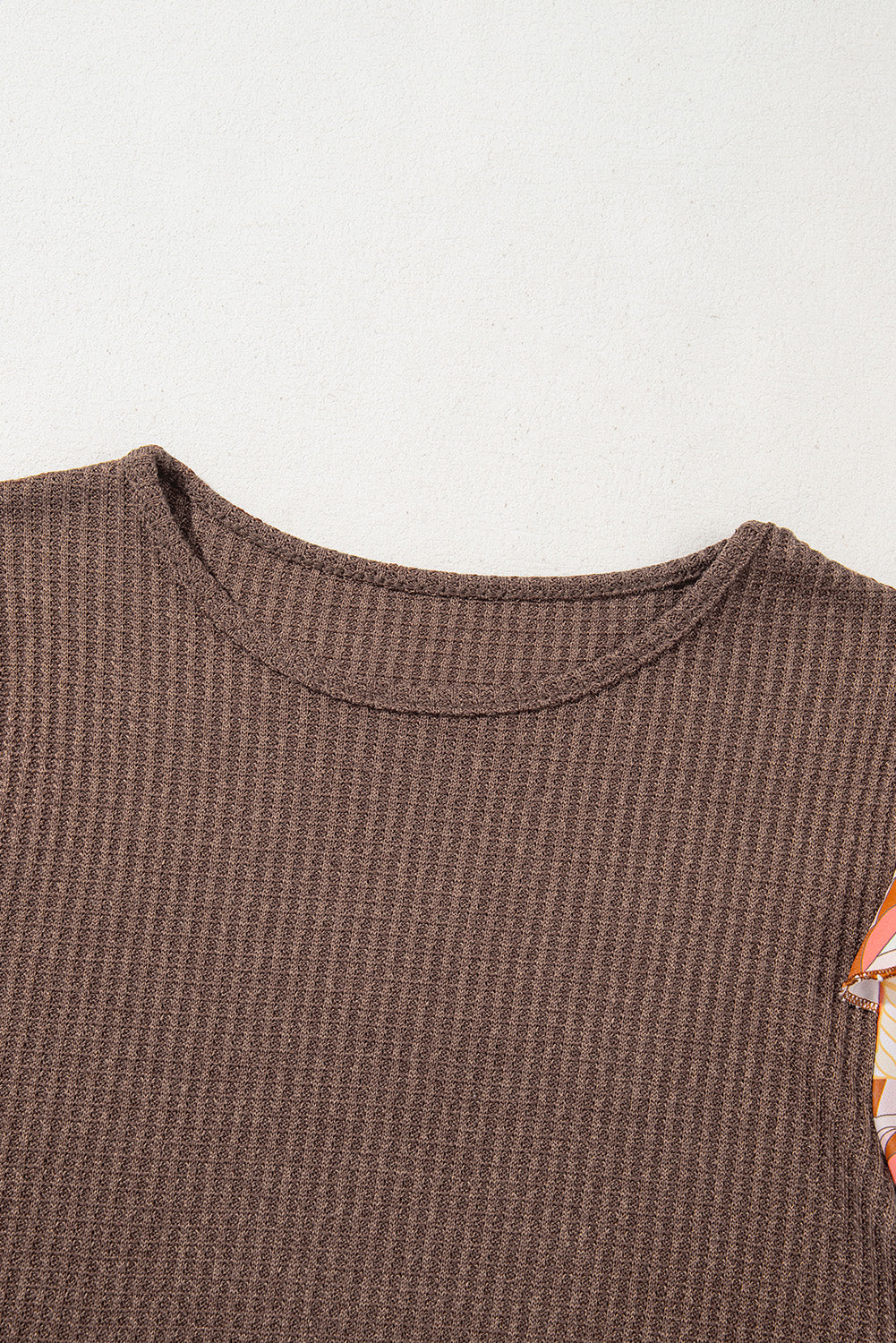 Brown textured sleeveless top with a colorful geometric pattern on a light gray background