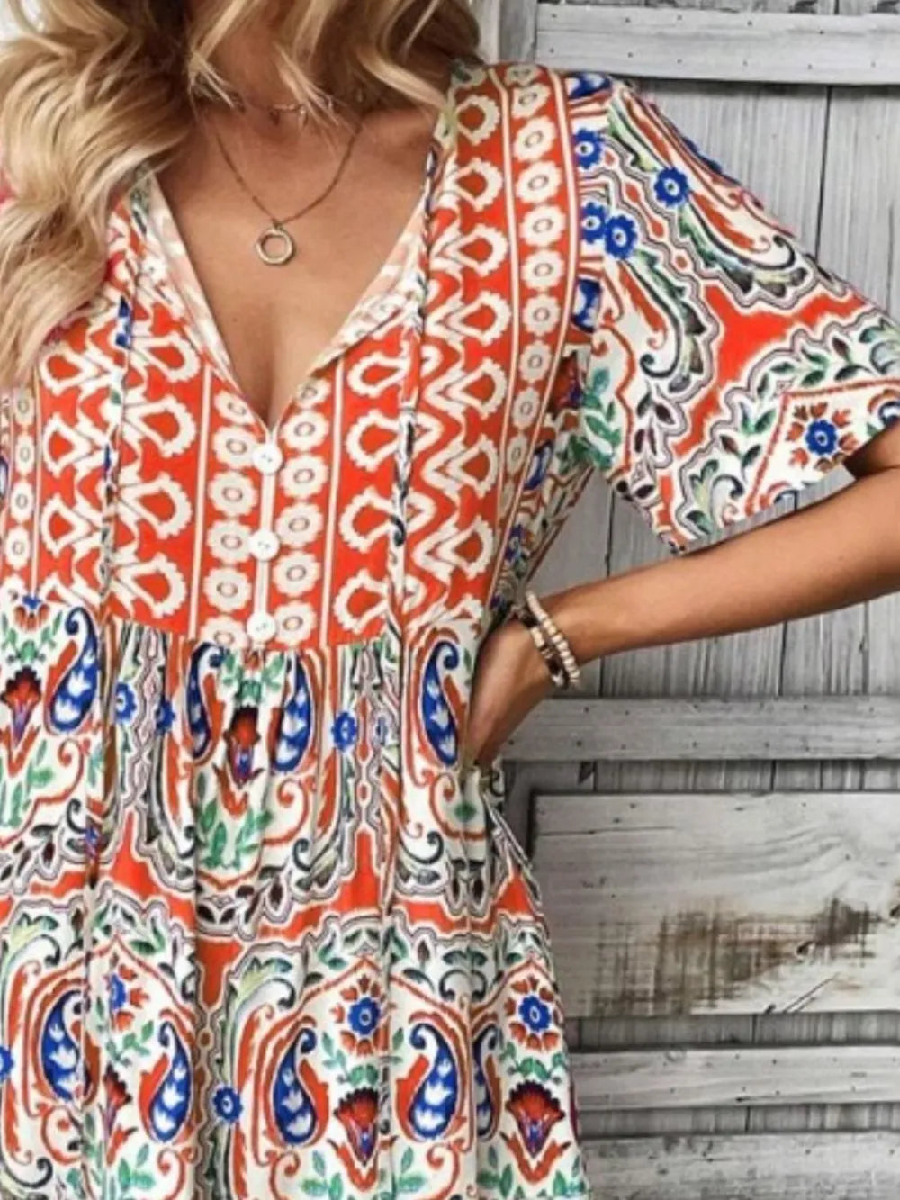 Woman wearing a colorful patterned dress with a neutral background