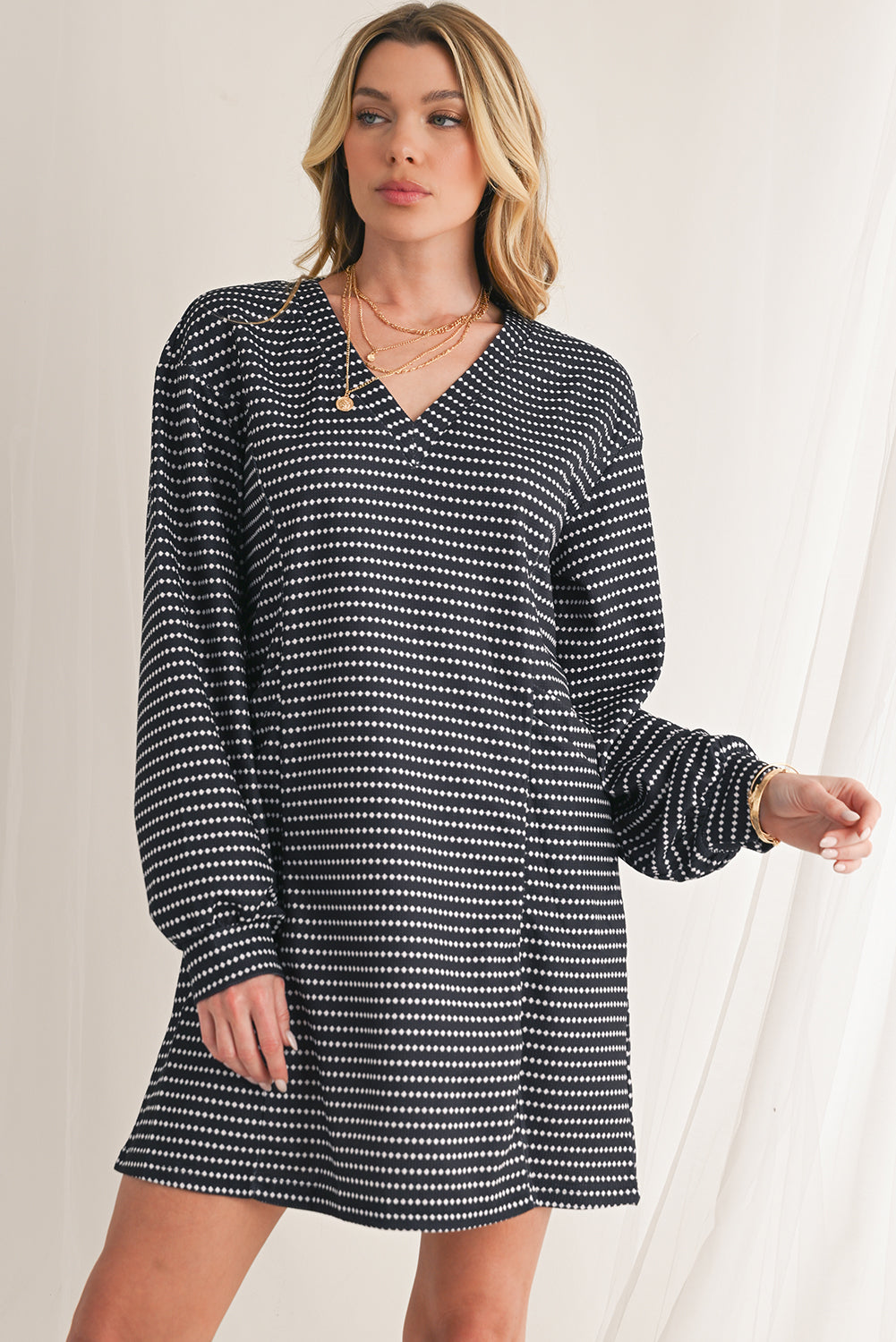 Woman wearing a black and white patterned dress against a neutral background