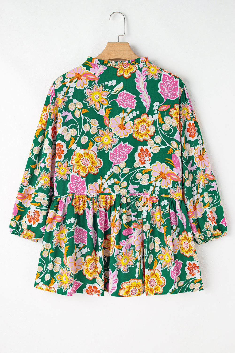 Floral dress with long sleeves on a hanger against a white background