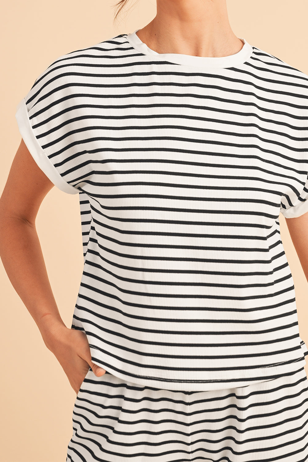 Black and white striped t-shirt worn by a person on a beige background