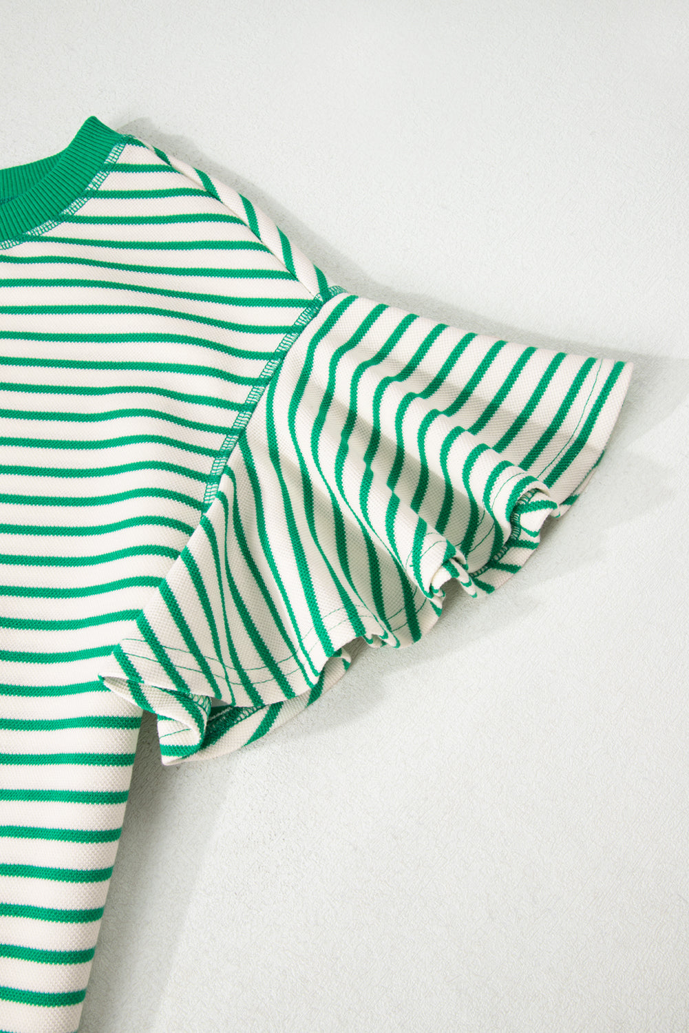 Green and white striped outfit with ruffled sleeves on a light gray background