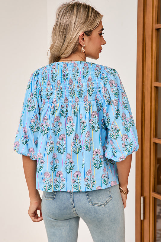 Woman wearing a light blue floral blouse with a neutral background