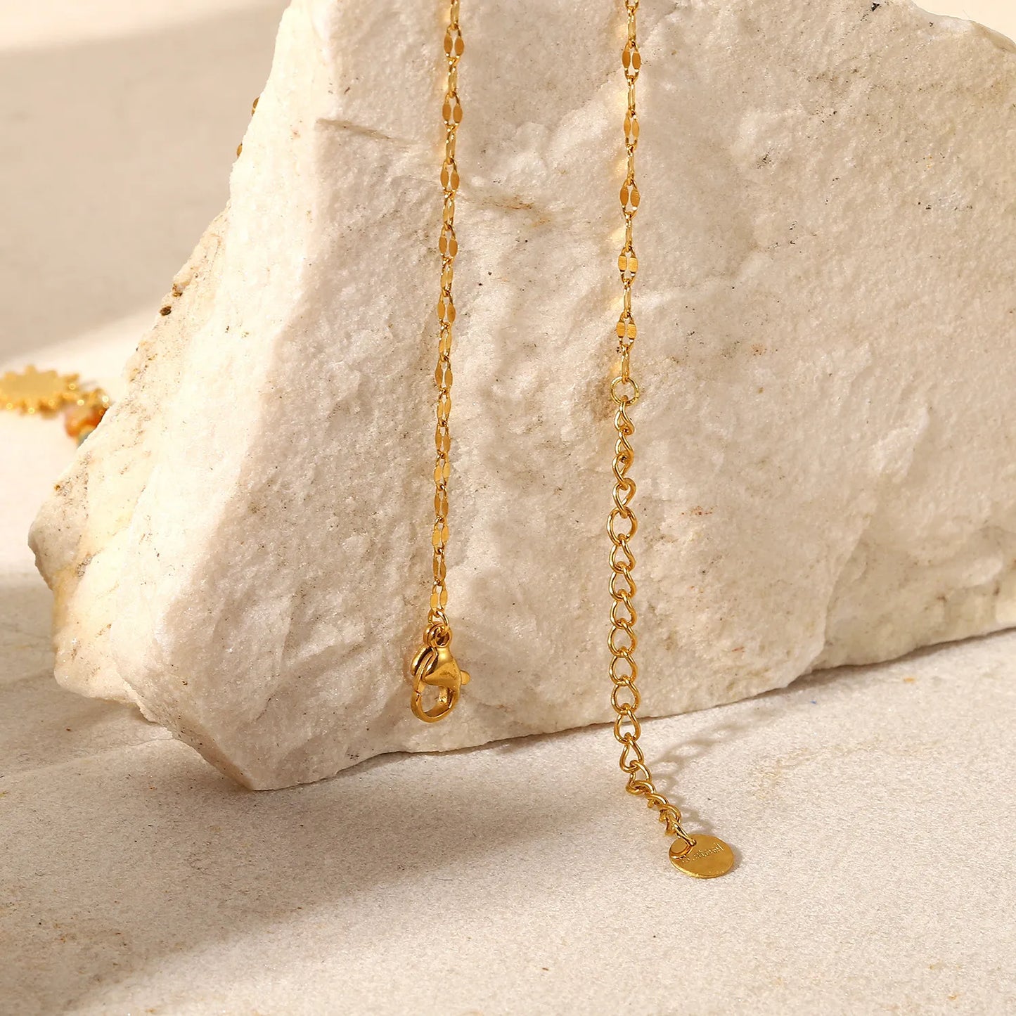 Gold necklace with a heart pendant on a stone surface