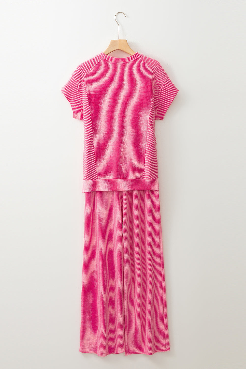 Pink outfit with a top and long skirt on a hanger against a white background